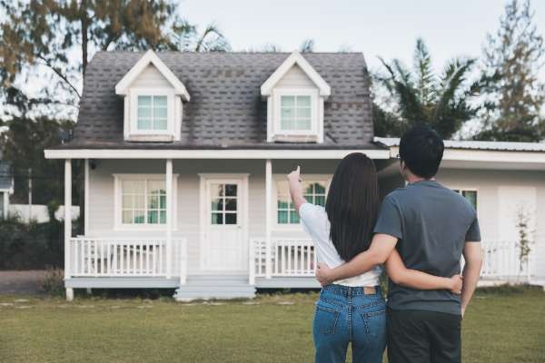 A couple standing outside pointing at a house in this image from Shutterstock