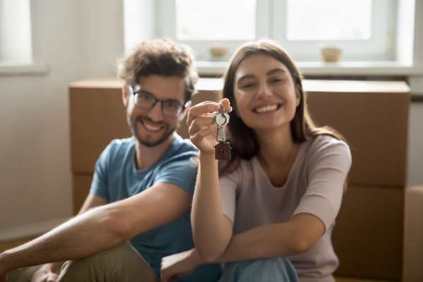 Woman and man smiling, holding house keys in this image from Shutterstock