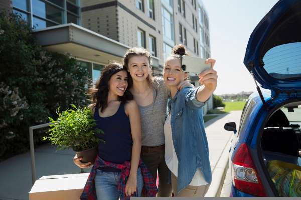 Three girls taking a selfie by a car outside in this image from Shutterstock