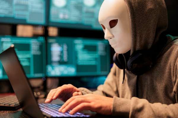 A masked man using a laptop in this image from Shutterstock 