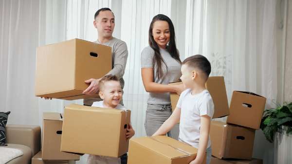A family of four each holds a cardboard box with handles