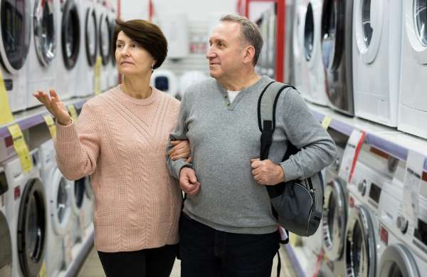 An older couple browses washing machines for sale at an appliance store in this image from Shutterstock