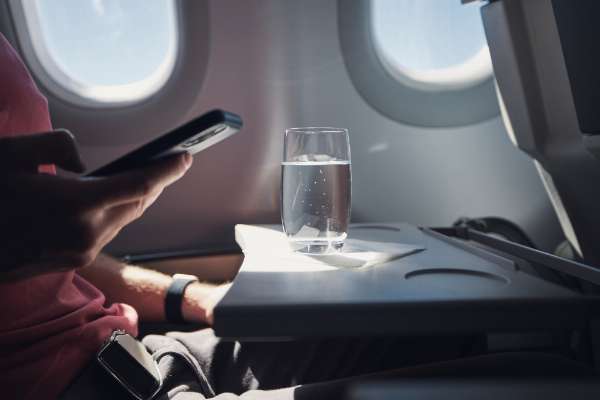 A glass of water on a table seat in an airplane in this image from Shutterstock