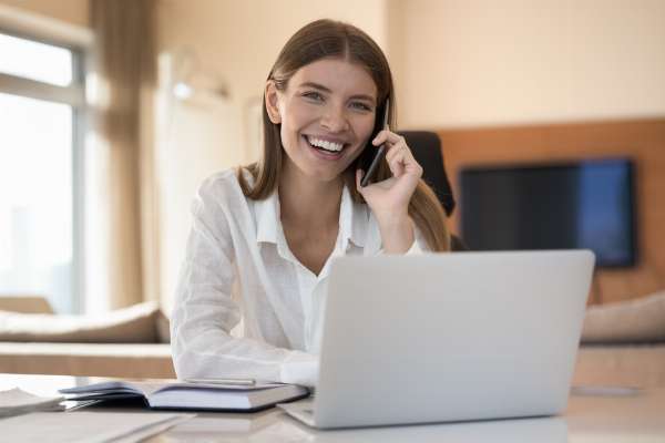 Woman holding a phone to her ear and smiling broadly, presumably because she’s a satisfied customer in this image from Shutterstock