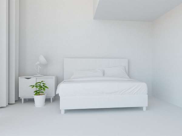 White room with a white-colored bed, bedside table, and lamp in this image from Shutterstock